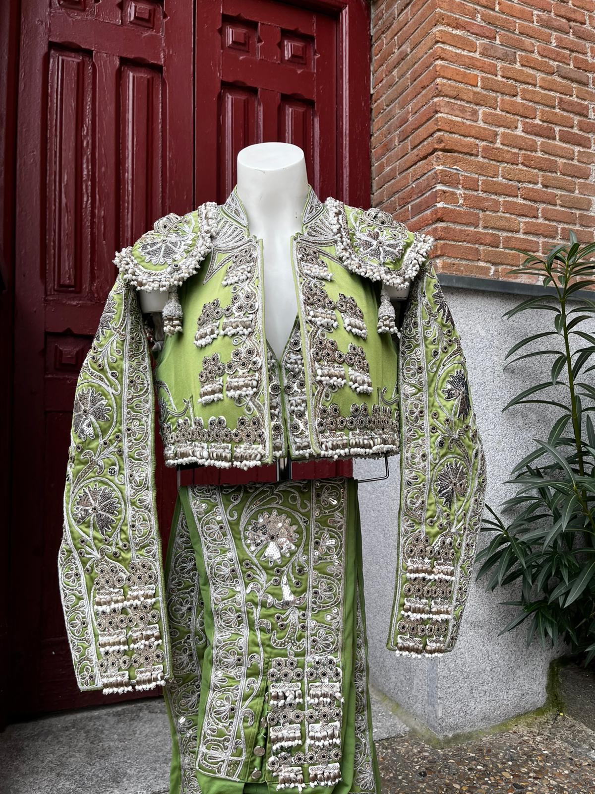 Chaquetilla y calzón verde y plata sobre percha de sastrería taurina